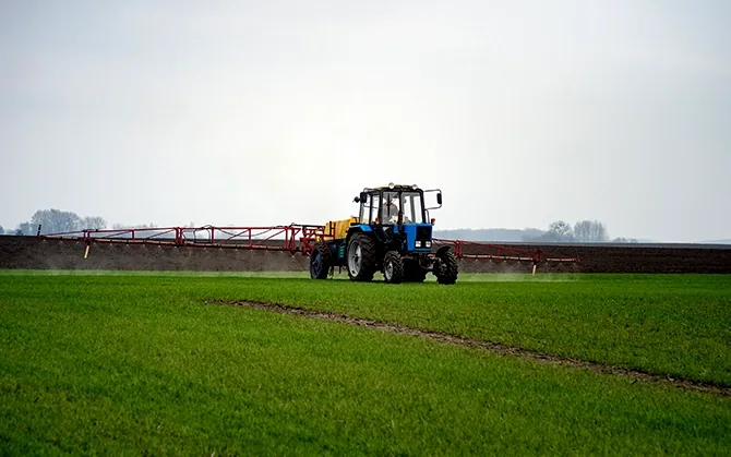 Tractor spraying crops in an open field
